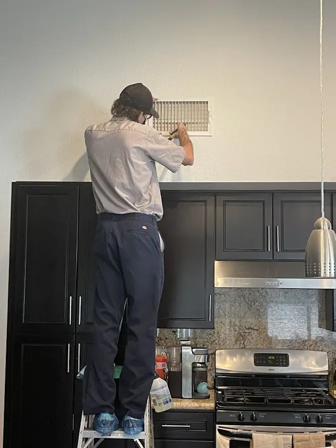 Technician inspecting an air vent during HVAC service in Shorewood